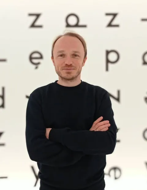 Artur with his arms folded in the letters background